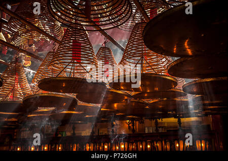 Lichtstrahlen Streaming in Man Mo Tempel hinter der großen Weihrauch Spulen an der Decke des Tempels, Hongkong, China, Asien Stockfoto