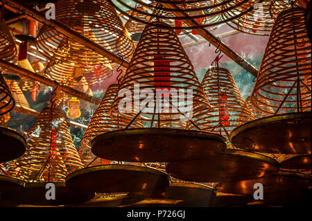 Lichtstrahlen Streaming in Man Mo Tempel hinter der großen Weihrauch Spulen an der Decke des Tempels, Hongkong, China, Asien Stockfoto