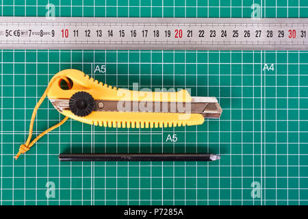 Cutter, ruller und Bleistift auf einem grünen Schneidematte Hintergrund Stockfoto