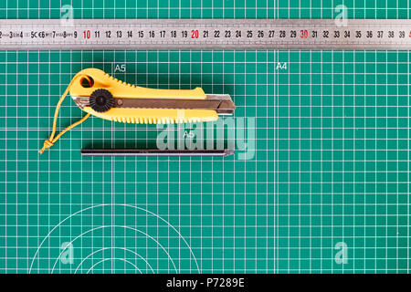 Cutter, ruller und Bleistift auf einem grünen Schneidematte Hintergrund Stockfoto