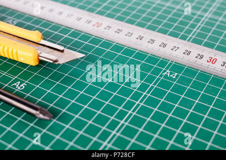 Cutter, ruller und Bleistift auf einem grünen Schneidematte Hintergrund Stockfoto