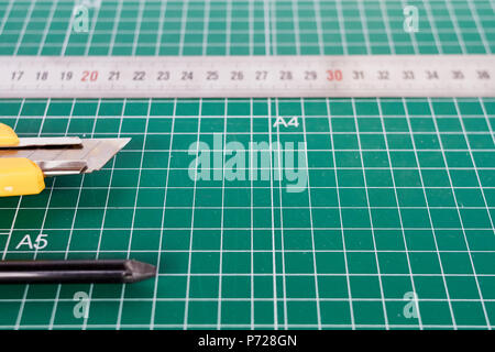 Cutter, ruller und Bleistift auf einem grünen Schneidematte Hintergrund Stockfoto