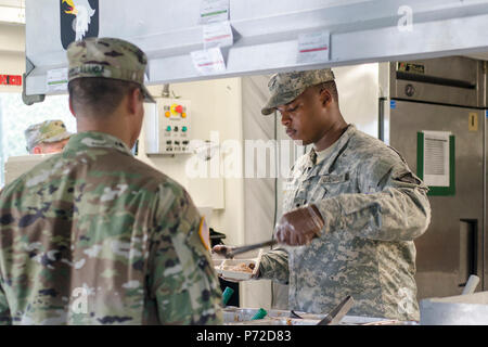 SPC. Ontroy Canty ein Food-Service-Spezialist, E Company, 101st Airborne Division, 6. Bataillon, 101. General Support Aviation Battalion, 101st Combat Aviation Brigade zugewiesen serviert Frühstück, Capt Capt Kris Sibbaluca in einer containerisierte Küche 11. Mai 2017 in Fort Campbell, Kentucky. Canty ist Bestandteil des Gerätes Philip A. Connelly Programm Bereich Fütterung Wettkampfteam, das gewann der Trennfläche im März und verbrachte fast zwei Monate Vorbereitung einer Website und training für den Korps-Ebene-Wettbewerb. Stockfoto