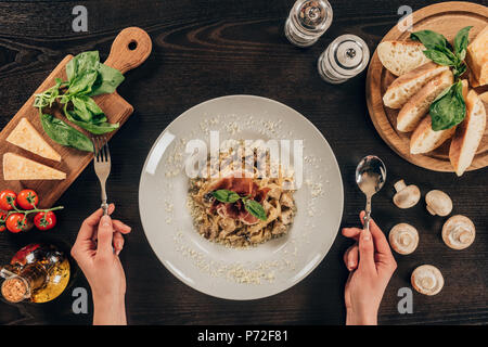 Zugeschnittenes Bild der Frau mit Gabel und Löffel und Pasta zu essen Stockfoto