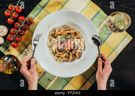 Zugeschnittenes Bild der Frau mit Gabel und Löffel und Pasta zu essen Stockfoto