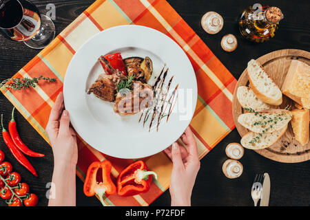 7/8 Bild der Frau, Platte mit gegrilltem Huhn auf dem Tisch Stockfoto