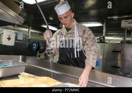 Meer (11. Mai 2017) Cpl. Jordan Feasel zu Bataillon Landung Team 3 Bataillon zugeordnet, 6 Marine Regiment (BLT 3/6) und einem toskanischen, Arizona native, Sprays essen Fächer, bevor Sie waschen in der spülküche der San Antonio-Klasse amphibious Transport dock Schiff USS Mesa Verde LPD (19) 11. Mai 2017. Das Schiff ist mit der bataan Amphibious Ready Gruppe implementiert Maritime Security Operations und Theater Sicherheit Zusammenarbeit in den USA 6 Flotte Bereich der Aktivitäten zu unterstützen. Stockfoto