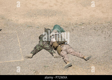 Ein Marine mit Task Force Südwesten Uhren für Auswirkungen auf Ziele als nationale afghanische Armee Soldat mit dem Helmand regionalen militärischen Training Center Brände eine M4 Carbine im Camp Shorabak, Afghanistan, 11. Mai 2017. Etwa 15 Marine Beratern sowie mit ANA Ausbilder, werden geplante erste operationelle der Task Force Bereitschaft Zyklus mit dem 2 Kandak, 4. Brigade 20. Mai zu beginnen. Das ORC ist so konzipiert, dass eine fähige und dauerhafte Kraft, die die afghanische Bevölkerung schützt und bestreitet sicheren Häfen zu den Aufständischen in der Provinz Helmand zu erstellen. Stockfoto