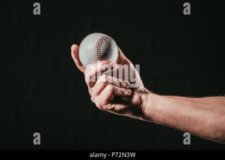 Close-up Teilweise mit Blick auf die männliche Hand baseball ball isoliert auf Schwarz Stockfoto