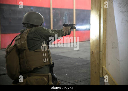 Dozenten mit Ausbildung Co., US Marine Corps Security Force Regiment zu prüfen, um ihre Studenten mit taktischen Bewertungen L-förmige Zimmer während der Close Quarters Battle 2-17 Kurs klar 10. Mai an Bord Naval Support Activity Nordwesten Anhang, Chesapeake, Virginia. Studenten auf ihre Fähigkeit, ein Zimmer zu löschen geprüft wurden und wie schnell Sie in der Lage sind, mögliche Bedrohungen und die Insassen zu adressieren. Stockfoto