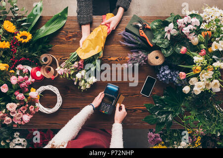 Zugeschnittenes Bild des Kunden das Bezahlen mit Kreditkarte für Bouquet Stockfoto