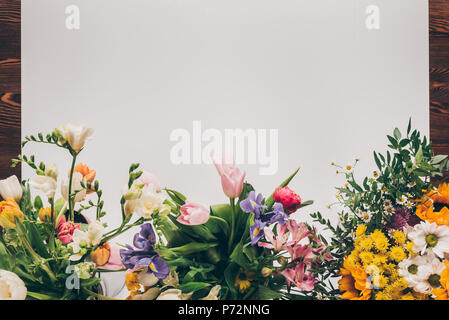 Blick von oben auf die weiße leere Blatt Papier mit bunten Blumen auf hölzernen Tisch Stockfoto