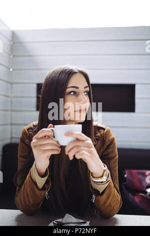 Hübsche Brünette junge Frau im Cafe Bar und trinken Kaffee sitzen. Stockfoto