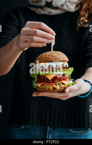 7/8-Ansicht von Frau mit großen traditionellen amerikanischen Cheeseburger Stockfoto