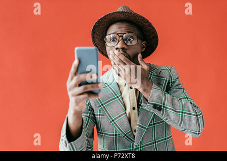 Junge schockiert afrikanische amerikanische Mann an Smartphone suchen, Rot, isoliert Stockfoto