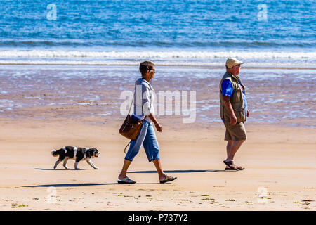 Ein paar Gehminuten Ihren Hund am Meer an einem sonnigen Tag bei niedrigen Newton am Meer, Northumberland, Großbritannien. Juli 2018. Stockfoto