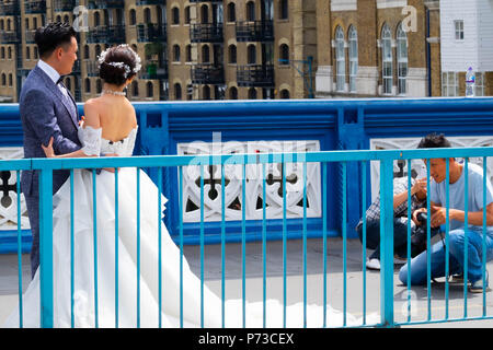 London, England. 4. Juli 2018. Ein paar haben ihre Hochzeitsfotos auf der Londoner Tower Bridge unter all den Touristen, die auf ein sehr heißer Tag. Die derzeitige Hitzewelle wird sich fortsetzen. © Tim Ring/Alamy leben Nachrichten Stockfoto