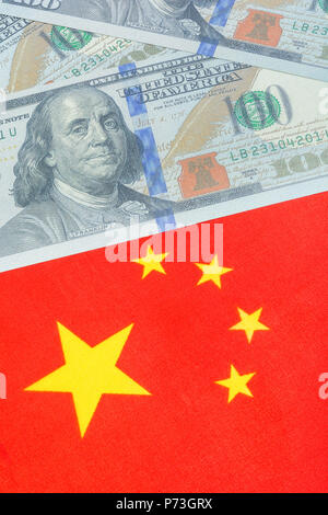 Chinesische Flagge + US-Dollar-Scheine/Banknoten. Für den Handelskrieg zwischen den USA und China, chinesische Zölle auf US-Sojabohnen. Lebensechte $100 Schulungsanforderung, US-China-Streit. Stockfoto