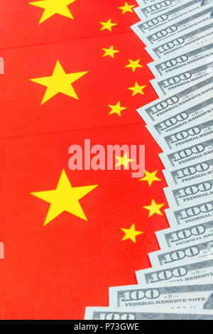 Chinesische Flagge + US-Dollar-Scheine/Banknoten. Für den Handelskrieg zwischen den USA und China, chinesische Zölle auf US-Sojabohnen. Lebensechte $100 Schulungsanforderung, US-China-Streit. Stockfoto