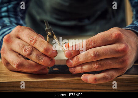 Eine Nahaufnahme eines männlichen Tischler Marken aus einem Metall Kompass und einen Bleistift auf eine Bar aus Holz für die Herstellung von Möbeln. Stockfoto