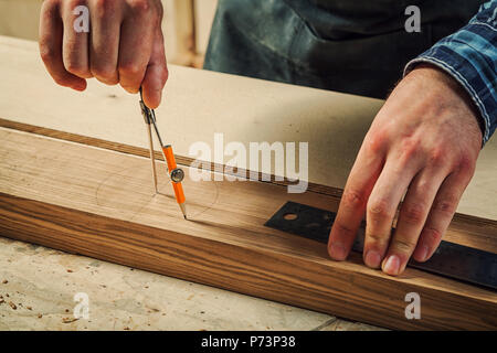 Eine Nahaufnahme eines männlichen Tischler Marken aus einem Metall Kompass und einen Bleistift auf eine Bar aus Holz für die Herstellung von Möbeln. Stockfoto