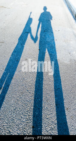 Der Schatten von einem Erwachsenen und einem Kind auf der Strecke. Stockfoto