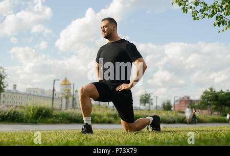 Jungen attraktiven Mann tun Ausfallschritt outdoor. Stockfoto