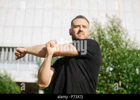 Attraktiver Mann zu tun stretching Hände Übungen, auf Park Hintergrund. Stockfoto