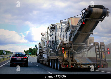 Auflieger Transportiert große Metso Brecher im Verkehr auf der Autobahn, hintere Ansicht von überholenden Autos, Staub von der Straße. Salo, Finnland - 30. Juni 2018. Stockfoto