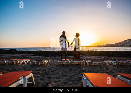 Freude und Liebe Konzept für die schwarze Rasse afrikanische Paar am Strand und liebevoll die Hände mit einem sehr schönen Sonnenuntergang farbige vor Stockfoto