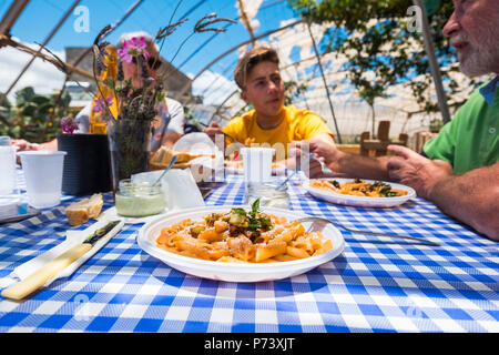 Nahaufnahme der Pasta alla Norma italienisch typische Speisen. Familie Kaukasier, genießen eine alternative Restaurant in der Natur im Freien. Alle bio und veget Stockfoto