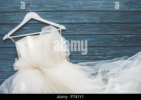 Blick von oben auf die weisse Hochzeit Kleid auf Aufhängevorrichtung für Holz- dunkel blau Tischplatte Stockfoto