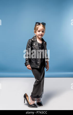 Adorable elegante kleine Mädchen mit großen Fersen, schwarzes Kleid und Jacke und Kamera suchen Stockfoto