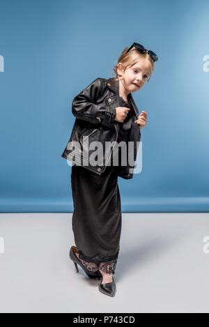 Adorable elegante kleine Mädchen mit großen Fersen, schwarzes Kleid und Lederjacke Stockfoto