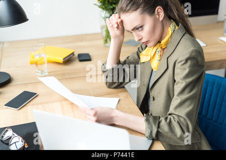 Hohe Betrachtungswinkel und der fokussierten Geschäftsfrau holding Papier beim Sitzen am Arbeitsplatz Stockfoto