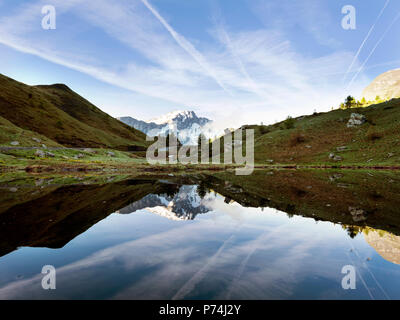 Die schneebedeckten Berge in der Nähe von Col de Vars in der französischen Provence im Wasser der kleine See spiegeln Stockfoto