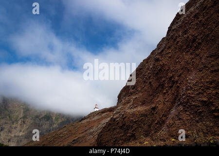 Die Gemeinde La Candelaria auf einem steilen roten Hügel mit grünen Berg, Frontera, El Golfo, El Hierro, Kanarische Inseln, Spanien Stockfoto