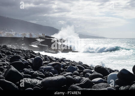 Riesige splash auf dunklen wavebreakers entlang der schwarzen Lava stein Küste bei Puerto de la Cruz, Teneriffa, Kanarische Inseln, Spanien Stockfoto