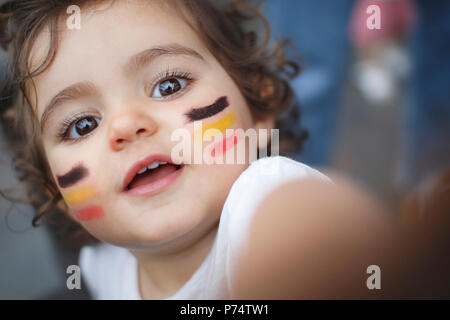 Kid Lüfter mit schwarz-gelb-rote Flagge auf Gesicht malen Stockfoto