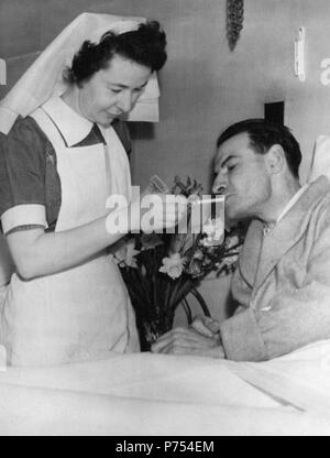 Foto vom 01/02/53 der National Health Service (NHS) Krankenschwester Nancy Lennox, eine Zigarette für James Blair, der aus der Versenkung des britischen Transport Kommission MV Prinzessin Victoria während eines Sturms gerettet wurde, als er im Bett in Bangor, Nordirland erholt. Stockfoto