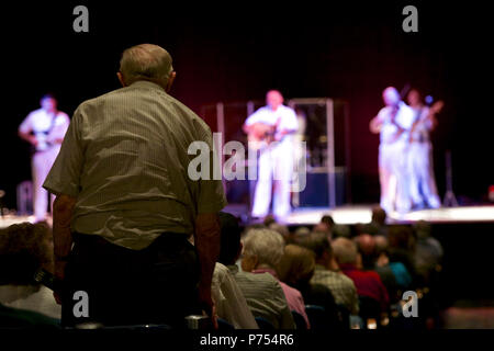 SCOTTSBLUFF, Neb. (Sept. 13, 2015) eine Marine Corps Veteran steht während des Marine Corps Hymne an einem US-Marine Band Land aktuelle Leistung an der Mittelwesten Theater in Scottsbluff, Neb. Tour der Marine Band empfohlene 14 Aufführungen in sechs Mitgliedstaaten, zu erreichen, die Gemeinschaften, die nicht in der Regel die Marine bei der Arbeit sehen. Stockfoto