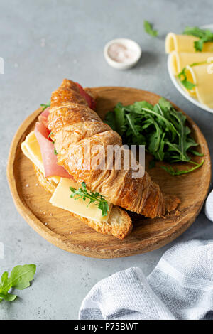 Leckere croissant Sandwich mit Schinken und Käse auf konkreten Hintergrund. Ansicht von oben. Breakfast Sandwich Stockfoto