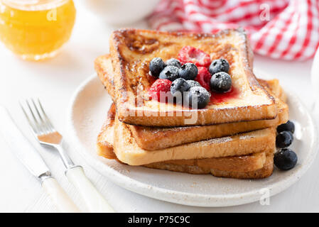 Hausgemachte französische Toast mit frischen Beeren und Honig auf weiße Platte, Detailansicht. Traditionelle süße Frühstück essen Stockfoto