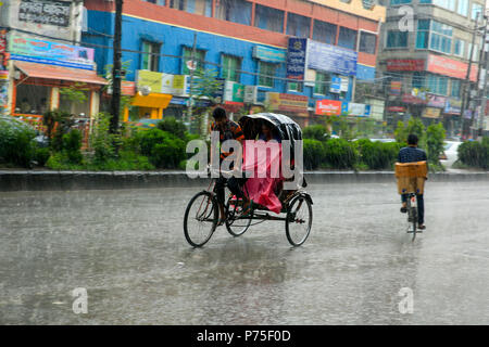 Eine Rikscha Abzieher trägt seine Passagiere in der regnerischen Tag, Dhaka, Bangladesch. Stockfoto