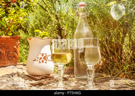 Abdeckung von frischen Landwein mit rustikalen Krug und einer Flasche Wasser, im Süden von Italien serviert. Die Gläser sind mit weißen Wein und Wasser gefüllt. Stockfoto