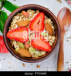 Frisches Müsli, Müsli mit Erdbeeren, Mandeln, Erdnüsse und Samen in einer Keramikschale auf weißem Hintergrund Holz, selektiver Fokus, getönten Foto Stockfoto