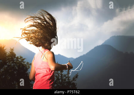 Kleines Mädchen mit ihrem Haar im Wind hört Musik mit Player und Kopfhörer. Stockfoto