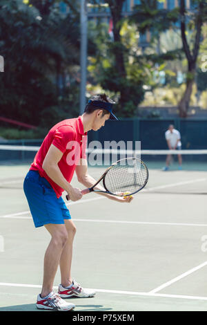 Asiatische tennis player bereit zu Beginn eines doubles Mixed Match zu dienen. Stockfoto