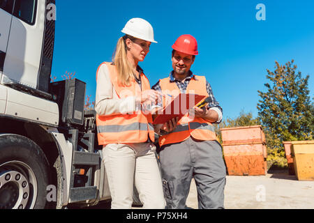 Arbeitnehmer Unterzeichnung Papiere zu Abriss Bauschutt Container geliefert Stockfoto