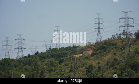 Strommasten und hohe Spannung, die durch die Berge der Cordillera. Philippinen, Luzon. Hohe Spannung Metall post, Turm. Elektrische Stromleitungen über Bäume. Stockfoto
